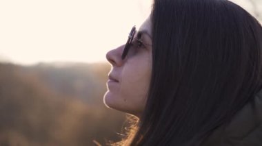Güneş gözlüklü hayalperest kadın gün batımının tadını çıkarıyor.