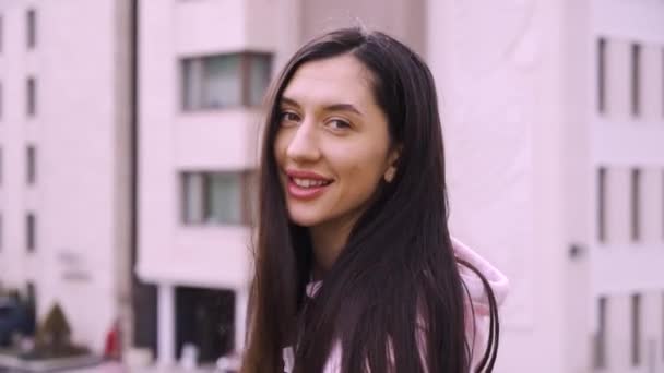 Positiv fröhliche Frau lächelt auf einem Balkon sitzend und zeigt — Stockvideo