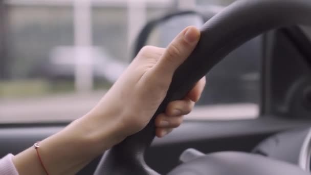Woman hand holding steering wheel, driving car in city traffic — Stock Video