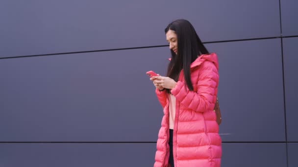 Sidovy av flicka i rosa skrattar när du använder sin smartphone — Stockvideo