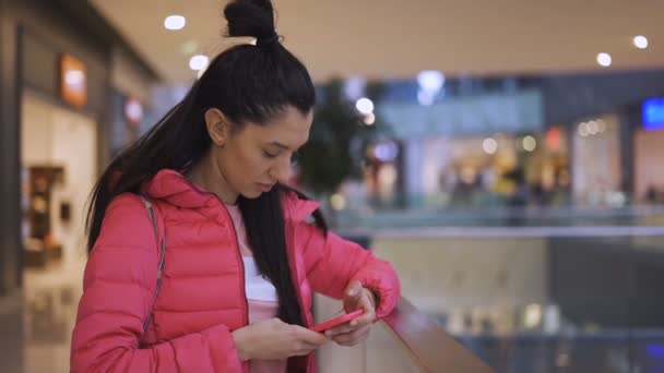 Joyful vrouw controleren smartphone na het winkelen vrouwen kleding in het winkelcentrum — Stockvideo