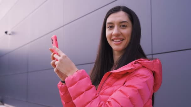 Dívka drží svůj smartphone s úsměvem na kameru — Stock video