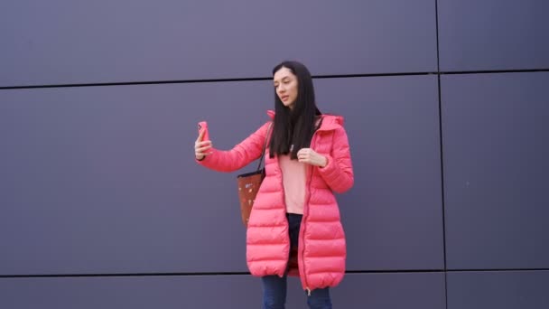 현대 벽에 셀카를 던지는 핑크 색 옷을 입은 세련 된 여성 — 비디오