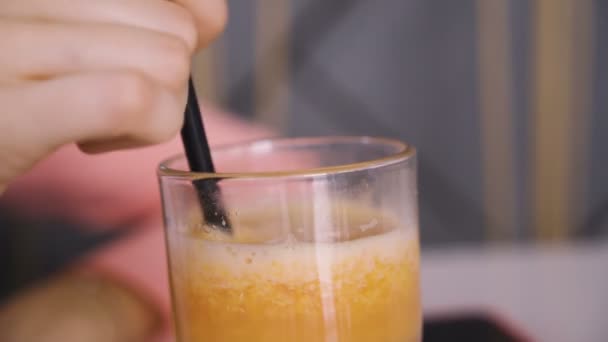 Женская рука перемешивает апельсиновый сок в ресторане — стоковое видео