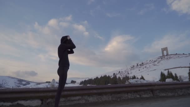 Fit vrouw in sportkleding voor te bereiden op de marathon in de bergen. Vrijheidsboog op de achtergrond — Stockvideo