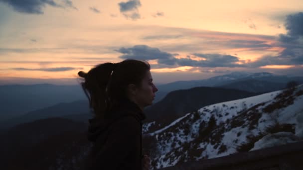 Entschlossene junge Frau läuft in kalter Winternacht mit malerischem Sonnenuntergang im Hintergrund — Stockvideo