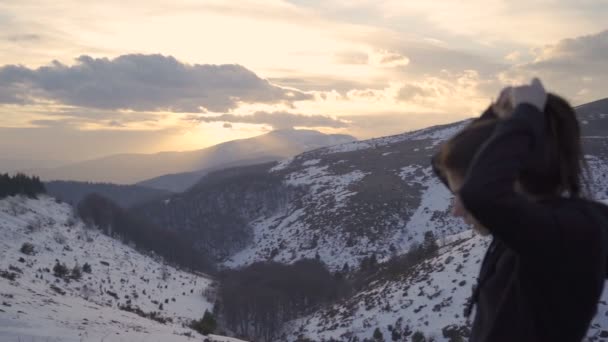 Schöne Frau fixiert ihre Haare und entspannt sich nach einem langen Marathon auf dem Gipfel des Berges bei Sonnenuntergang — Stockvideo