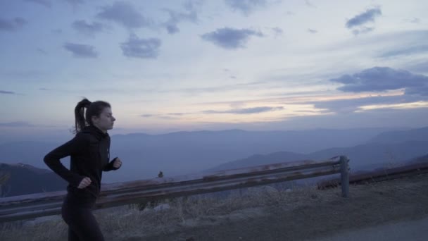 Ajuste jogger femenino con cola de caballo corriendo a la cima de la montaña al atardecer — Vídeos de Stock