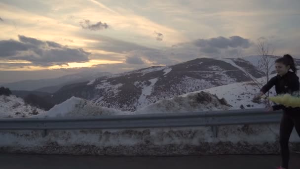 Sarı duman fişeğiyle dağlarda altın gün batımına karşı koşan heyecanlı genç kadın. Bulgaristan — Stok video