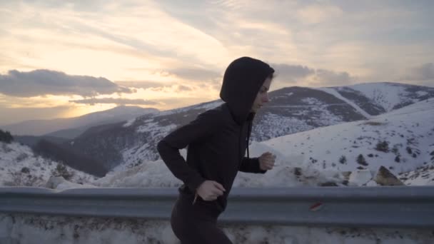 Koncentrerad fitness flicka kör, sprintning i kall vinterdag i bergen vid gyllene solnedgång — Stockvideo