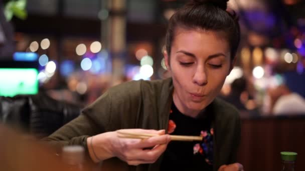 Kobieta jedząca pyszne jedzenie pałeczkami podczas rozmowy z przyjacielem — Wideo stockowe