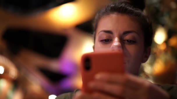 Mujer morena concentrada usando su teléfono inteligente, charlando o enviando mensajes de texto mientras cena en el restaurante — Vídeo de stock