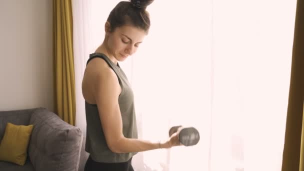 Sportig kvinna leende och träning hantlar hemma — Stockvideo