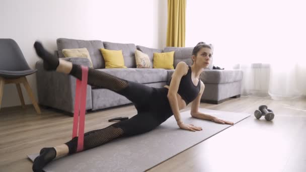 Donna sportiva che esercita con la fascia di resistenza nei vestiti di yoga — Video Stock