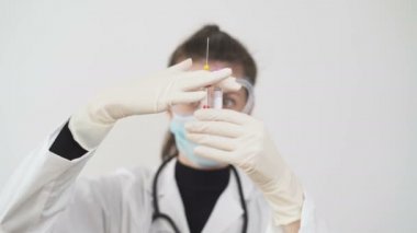 Beyaz önlüklü kadın doktor, koruyucu maske ve gözlük kan örneklerini kontrol et. Laboratuvarda koronavirüs testleri negatif.