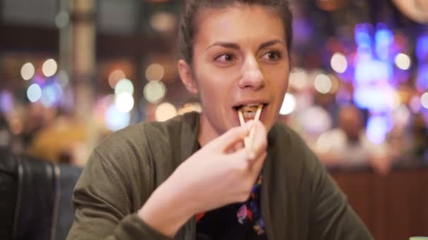 Menina sorrindo jantando com o amigo comendo alimentos com pauzinhos — Vídeo de Stock