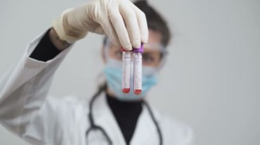 Beyaz önlüklü kadın doktor Coronavirus testleri için kanla test tüpleri tutuyor.