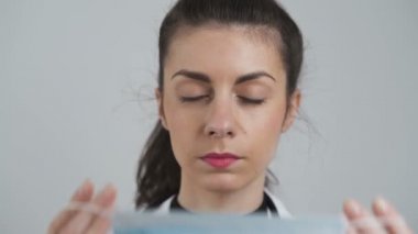 Genç bayan doktor ağız ve buruna yüz maskesi takıyor. COVID-19 'a karşı koruyucu tedbirler, yakın görüş