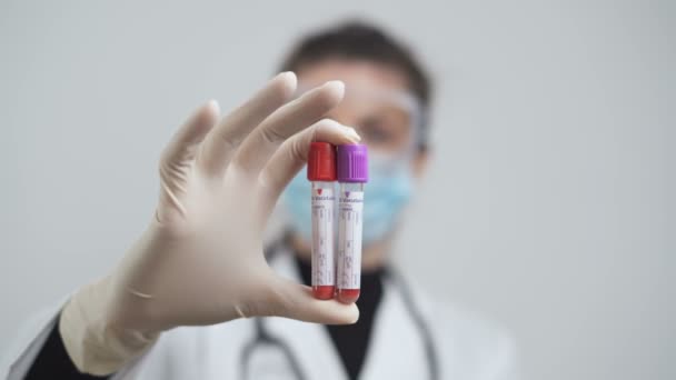Mão feminina segurando recipientes de sangue, tubos vacutainer no laboratório para testes de coronavírus — Vídeo de Stock
