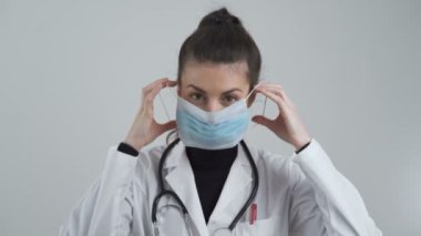 Genç bayan doktor 2019 Coronavirus Hastalığının Önlenmesi için ağız ve buruna nasıl yüz maskesi takılacağını gösteriyor.