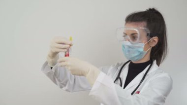 Laboratuvarda SARS-CoV-2 ile çalışan yüz maskeli ve koruyucu gözlüklü bir doktor. COVID-19 salgın krizi