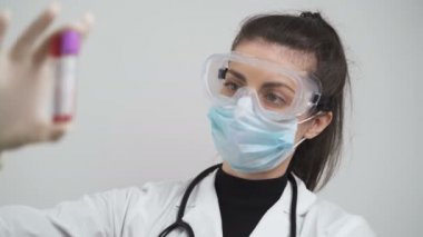 Doktor, sondalar arasındaki kan ve not farklılıklarının test tüplerini tutuyor.