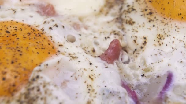 Крупный план яиц на сковородке. Соленые и пряные яйца с кубиками бекона — стоковое видео