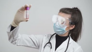 Beyaz önlüklü ve eldivenli kadın Coronavirus Kan Testlerini Hastane Laboratuvarında kontrol ediyor.