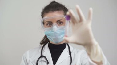 Eldivenli, koruyucu maskeli ve gözlüklü Coronavirus kan testi tutan doktor.
