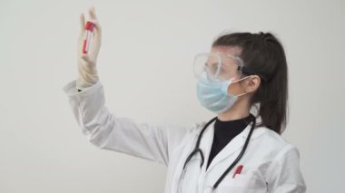 Kadın bilim adamı, kan örneklerini ya da serumları karşılaştırıyor. Laboratuvarda hastalarda koronavirüs testi yapılıyor.