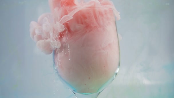 Tinta abstracta en vaso de agua. Niebla rosa sedosa en vidrio — Vídeos de Stock