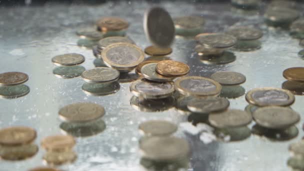 Plata y monedas de oro cayendo bajo el agua en cámara lenta y creando burbujas — Vídeo de stock