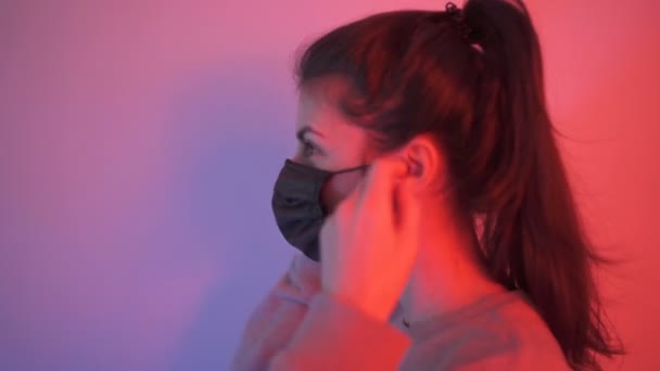 Vrouw kijken naar de camera en zet bescherming masker — Stockvideo