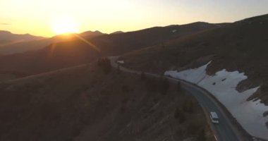 Gün batımında dağ yolundan geçen beyaz kargo minibüsü ya da otobüs.