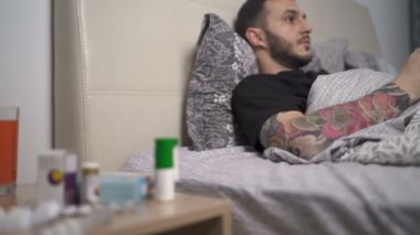 Evde karantinada yatan bir adam yatakta video oyunları oynuyor.