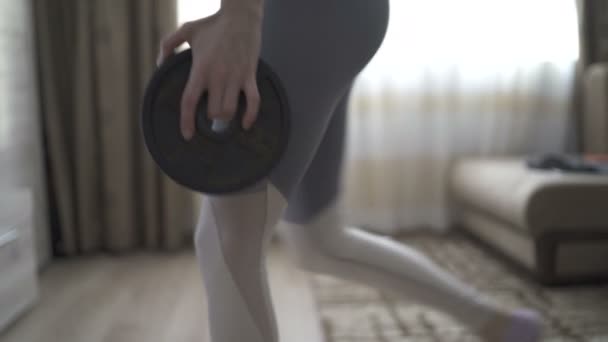 Hermosa atlética mujer haciendo dumbbell embestidas en casa — Vídeo de stock