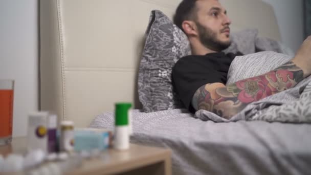 Мужчина в домашнем карантине играет в видеоигры, лежащие в постели — стоковое видео