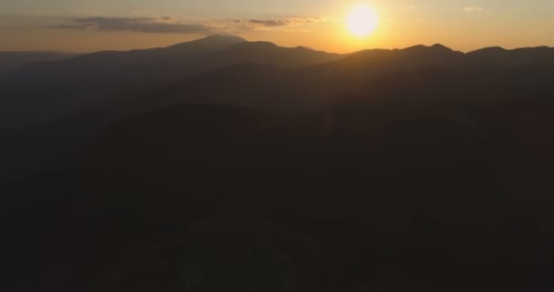 Siluetas de montañas y colinas sobre el fondo de un sol dorado al atardecer y oscuras nubes nocturnas — Vídeos de Stock