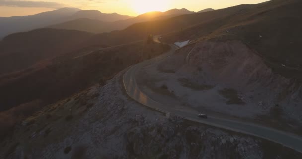 Czarny samochód jadący samotną górską drogą o świcie. Podróż wiosną — Wideo stockowe