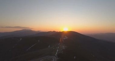 Gökyüzü açık dağların üzerinde güzel bir gün batımı