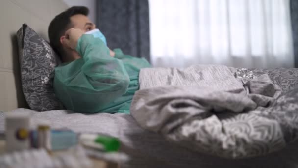 Hombre enfermo infectado con el virus tosiendo y poniendo mascarilla. Cuarentena en casa — Vídeos de Stock