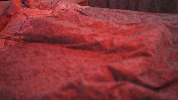 Uzależniony mężczyzna w czarnej masce grający w gry wideo podczas izolacji w swojej czerwonej, świecącej sypialni — Wideo stockowe