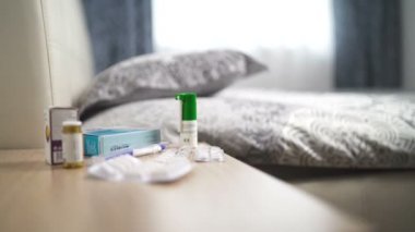 Boğaz spreyi, beyaz kapsüllü kabarcıklar ve gün içinde yatak odasındaki komodinin üzerine haplar.