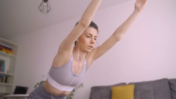 Enerjik yoga yapan kadının düşük açılı görüntüsü, kollarını uzatması, evde egzersiz yapması. — Stok video