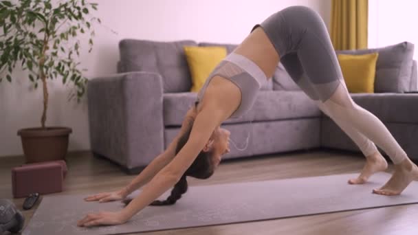 Slim meisje in Down hond yoga pose stretching armen — Stockvideo