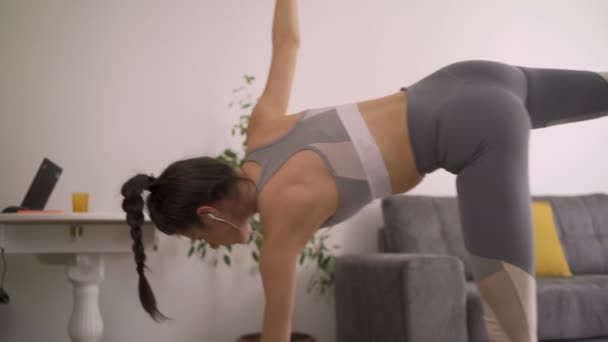 Mujer practicando yoga moderno en casa. Mujer flexible en posición de ángulo lateral difícil . — Vídeos de Stock