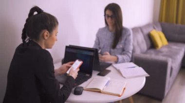 Karantina sırasında cep telefonları ve dizüstü bilgisayarlar kullanarak evde çalışan iş kardeşleri.
