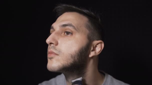 Крупним планом чоловік обрізає і формує бороду, ізольовано на чорному тлі — стокове відео