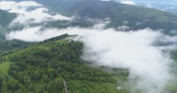 Letecký pohled na zelené kopce a pastviny pokryté hustou bílou mlhou — Stock video