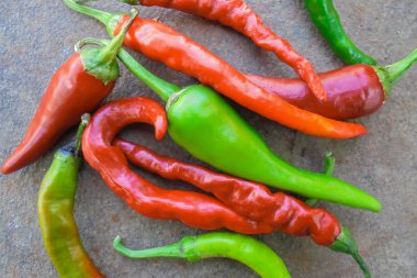 Kırmızı, yeşil, turuncu, farklı şekillerde acı biberler eski paslı bir metal yüzeyde yatar. Yukarıdan görünüm